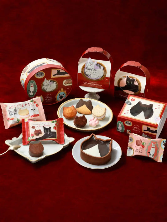 The NEKO NEKO Winter Museum 2026 collection arranged on deep red satin, with the round museum tin, gift boxes and cat-shaped sweets