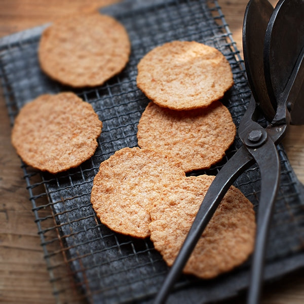 Freshly baked Yukari shrimp crackers cooling on a wire rack with a traditional baking iron