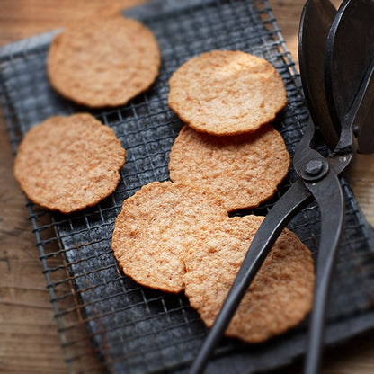Freshly baked Yukari shrimp crackers cooling on a wire rack with a traditional baking iron